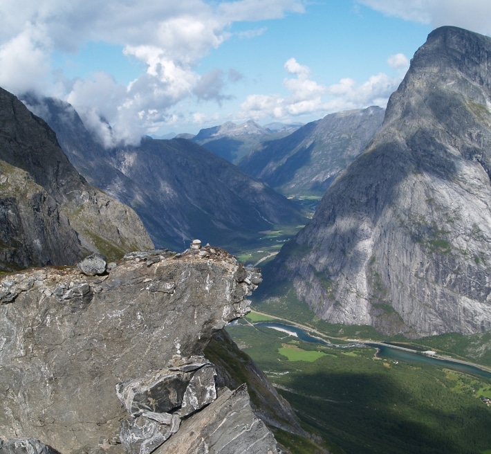 Romsdalen betyr ”Raumas dal”, etter den strie elva som renner gjennom dette helnorske landskapet. Det trange dalføret, som strekker seg fra Åndalsnes i nord til Lesjaskogsvatnet i sør, er viden kjent for de majestetiske toppene Trolltindene og Romsdalshorn, samt Trollveggen hvor det stadig løsner små skred (GEO 02/1998). Trollveggen har oppnådd internasjonal berømmelse fordi vi her finner Europas høyeste overhengende stup med et loddrett fall på mer enn 1000 m, men også fordi den nettopp derfor blir oppsøkt av både base- og fallskjermhoppere som setter livet til på sin jakt etter spenning. Rett sør for disse berømte fjellene, litt lenger inn i dalen, er det enda mer spenning, for her lurer skredfaren. Gapende sprekker i fjellsiden og brede rasvifter i dalbunnen vitner om ustabile fjellmasser. Mens lokalbefolkningen er godt kjent med små hyppige skred, sier geologene nå at store biter av fjellene like sør for Trolltindene kan gli ut. De små utrasningene kan være et forvarsel, en påminnelse om at større skred kan være på gang. Foto: Halfdan Carstens
