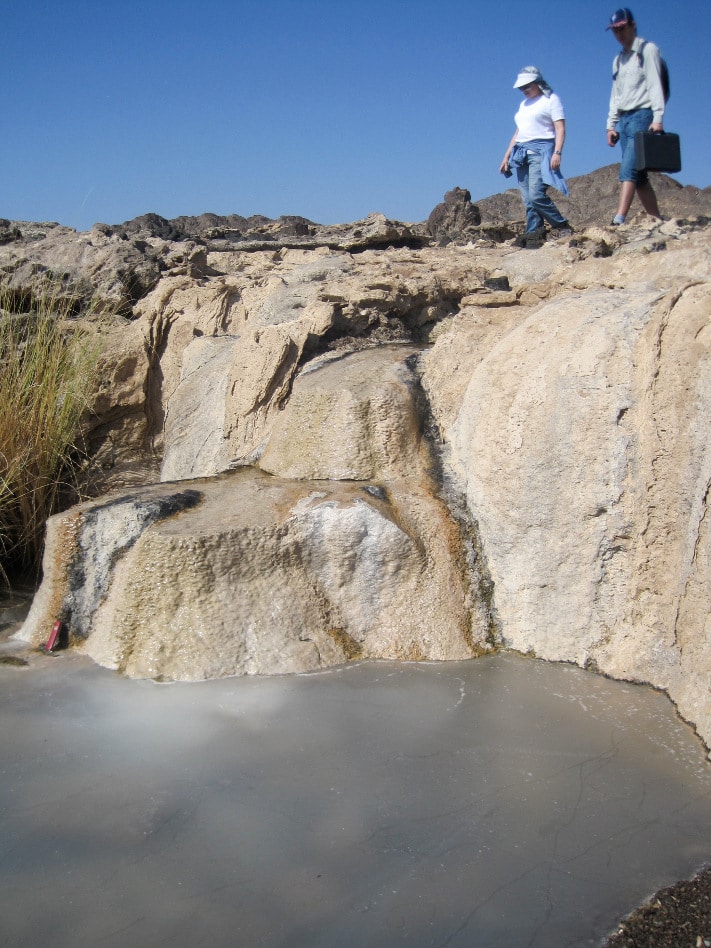 Travertine avsetninger knyttet til kilder av alkaline fluider i Samailofiolitten i Oman. Alkaline løsninger, med pH mellom 11 og 12 dannet under serpentiniseringsreaksjoner i dypet, suger til seg CO2 fra atmosfæren og feller ut kalsitt på overflaten. ”Isen” på dammen i nedre kant av bildet består også av et tynt lag kalsitt. Foto: Bjørn Jamtveit, PGP.