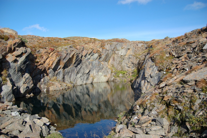 Kvernsteinsbruddene ble i løpet av våren, sommeren og høsten fylt med vann og det første arbeiderne måtte til med når de kom opp i fjellet utpå senhøsten, var å tømme dem for vann. Det var et slitsomt og tidkrevende arbeid. Bruddene lå da ofte gjenføket med snø og på vannet var det tykk is som måtte hugges opp før de kom til med sine treøser og bøtter. Foto: Karl H. Brox